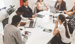 © xartproduction - A team of young office workers, businessmen with laptop working at the table, communicating together in an office. Corporate businessteam and manager in a meeting. coworking.