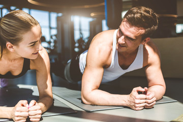 Canvas Print - Couple Woman and man in the gym is warming up before training, stands in plank