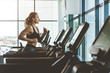 © xartproduction - The athletic woman dressed in a black sportswear running on the treadmill in the modern gym