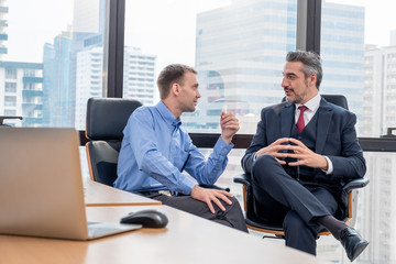 Young Caucasian worker sitting and discussion with Caucasian boss or CEO. about work in office