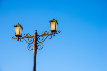 Two street lights against the blue sky. Urban architecture.