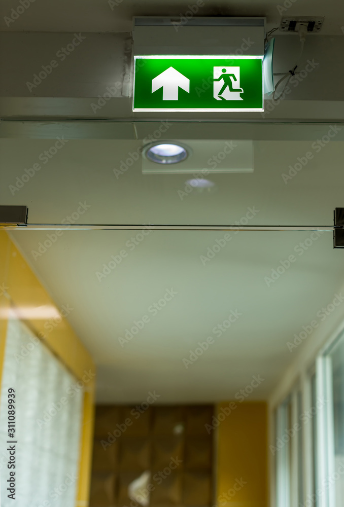Green emergency exit sign showing the way to escape.Fire exit in the ...