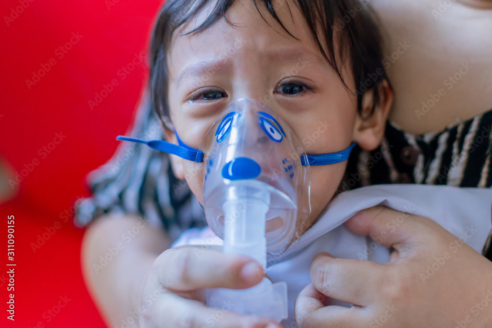 Sick boy inhalation therapy by the mask of inhaler. Baby has asthma and ...