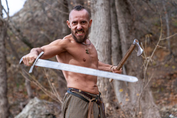 Armed Viking stands against the background of the forest