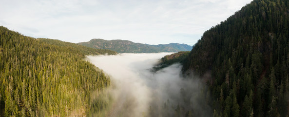 Wall Mural - Aerial Panoramic View of Beautiful Canadian Mountain Landscape above the clouds during a sunny day. Located on the West Coast of Vancouver Island near Tofino and Ucluelet, British Columbia, Canada.