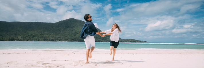 A pair of lovers have fun running around on a tropical beach.