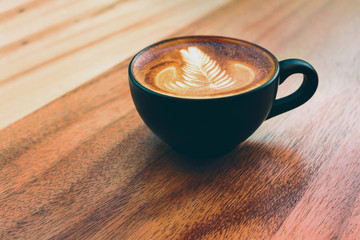 Wall Mural - Coffee mug of Latte art coffee breakfast on wood  table  in morning time with light from window  vintage cafe style