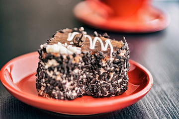 Wall Mural - A slice of chocolate cake in the shape of a heart on a red plate.