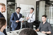 © xartproduction - A team of young businessmen working and communicating together in an office. Corporate businessteam and manager in a meeting.