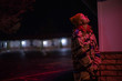 © Elijah Hurwitz - A young woman in a winter hat under a pink light from a cheap motel sign
