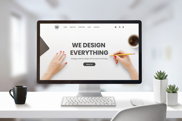 Poster - Web design studio concept with modern agency web page on computer display. Office, studio desk with cup of coffee and plants beside