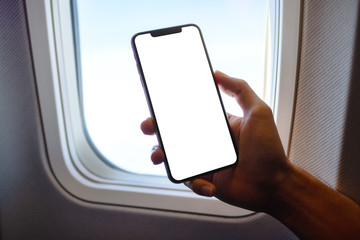 mockup image of a hand holding a black mobile phone with blank desktop screen next to an airplane wi