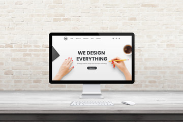 Poster - Modern computer display with web design agency page on office, studio desk. Flat design concept. Modern flat design interior with brick wall in background