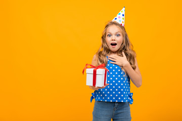 Wall Mural - Nice little girl with a birthday party holds a present isolated on white background