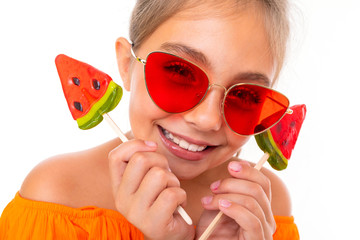 portrait of a tanned attractive tourist girl with a chupa lollipops in the form of a watermelon on a white background