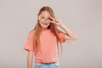 Wall Mural - Inclusive Beauty. Girl with freckles standing isolated on grey posing showing salute gesture cool