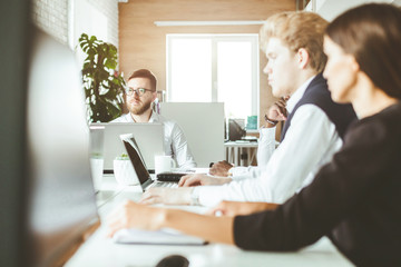 A team of young businessmen working and communicating together in an office. Corporate businessteam and manager in a meeting.