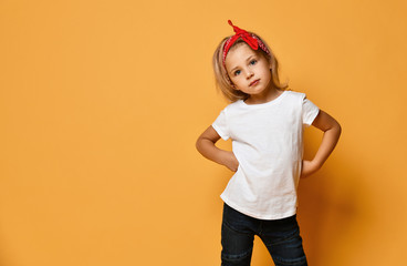 beautiful little girl in a white t-shirt and a red bandage on her head with blue eyes looks slyly on