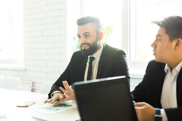 A team of young businessmen working and communicating together in an office. Corporate businessteam and manager in a meeting.