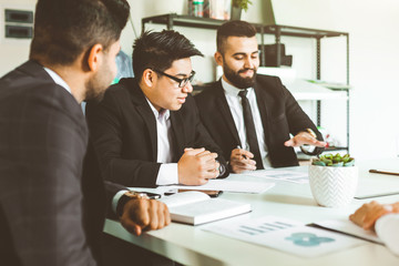 A team of young businessmen working and communicating together in an office. Corporate businessteam and manager in a meeting.