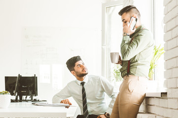 A team of young businessmen working and communicating together in an office. Corporate businessteam and manager in a meeting.