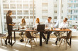 © xartproduction - A team of young businessmen working and communicating together in an office. Corporate businessteam and manager in a meeting. desktop against the background of the pan window, free space for text
