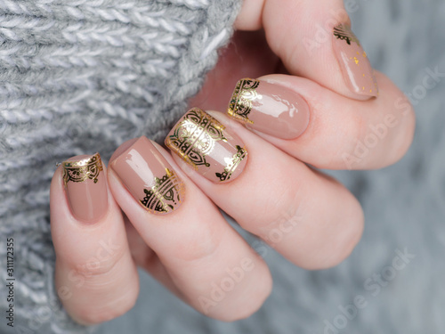 beige Nude manicure with gold lace pattern on a gray background Fototapet