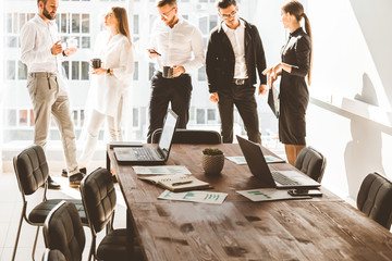 work area on the table in the foreground. A team of young businessmen working and communicating together in an office. Corporate businessteam and manager in a meeting.