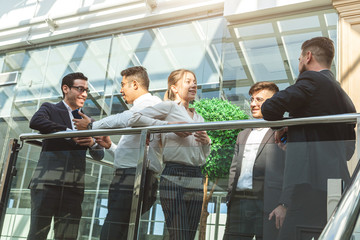 Sticker - young business people are standing and talking on the background of glass offices. Corporate businessteam and manager in a meeting.