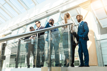 Sticker - young business people are standing and talking on the background of glass offices. Corporate businessteam and manager in a meeting.