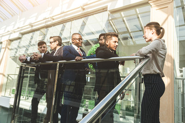 Sticker - young business people are standing and talking on the background of glass offices. Corporate businessteam and manager in a meeting.