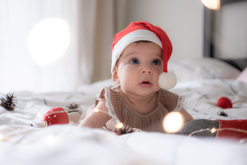 little cute baby girl portreit in red christmas santa hat with lights