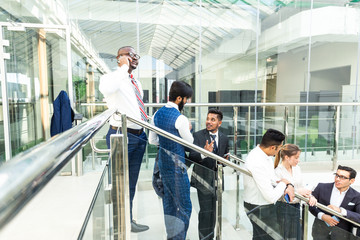 Sticker - young business people arego down the stairs and talking on the background of glass offices. Corporate businessteam and manager in a meeting.