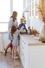 Mother with her kids cooking in the kitchen to xmas, casual lifestyle photo series in real life interior