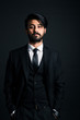 © xartproduction - Portrait of a young handsome successful Indian in a classic black three-piece business suit on a dark background