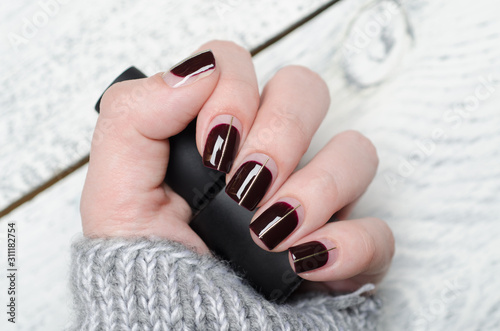 Stampa su Tela Burgundy manicure with negative space and Golden line on grey background