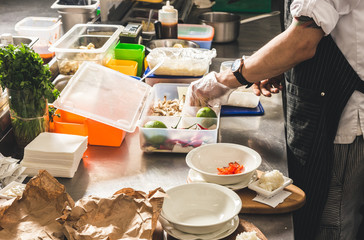 Professional chef cooking in the kitchen restaurant at the hotel, preparing dinner. A cook in an apron makes a salad of vegetables and pizza.