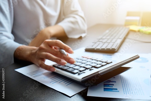 Fotomural The hand of Asian woman is pressing calculator and prepare information for report to correct
