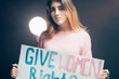 young caucasian feminist girl holding poster with inscription fight for women rights, calling for giving women rights, wearing casual trendy clothes
