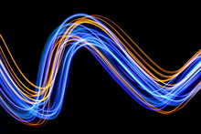 Long Exposure Photograph Of Neon Blue And Gold Colour In An Abstract Swirl, Parallel Lines Pattern Against A Black Background. Light Painting Photography.