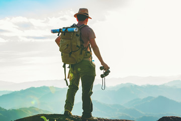 the hiker with a backpack stood on the rock after examining the map to find a path in a beautiful mo