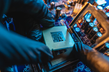 Wall Mural - Engineer repairman holding hands CPU to insert into the socket of the motherboard. Technology hardware in the neon light