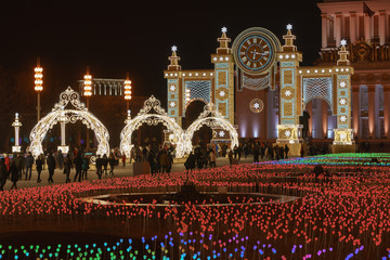 Wall Mural - Bright and colorful decoration of Exhibition of Achievements of National Economy in Christmas. People walking. Main pavilion of VDNkH in distance.