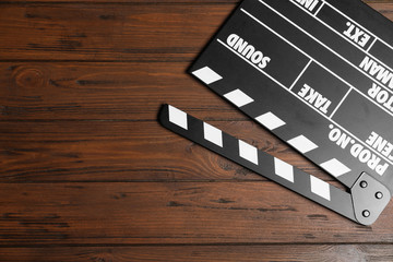 Clapperboard on wooden table, top view with space for text. Cinema production