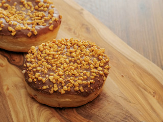 Two salted caramel doughnut with golden crumb on a wooden board and table.