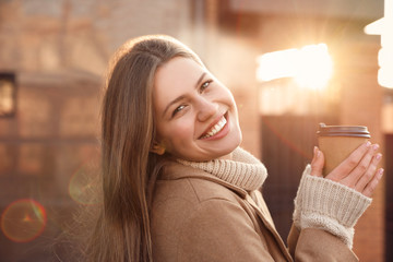 Wall Mural - Young woman with cup of coffee on city street in morning