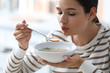 © New Africa - Young woman eating tasty vegetable soup indoors