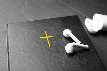 Bible and earphones on black table, closeup. Religious audiobook