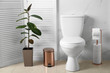 Ceramic toilet bowl and accessories in modern bathroom interior