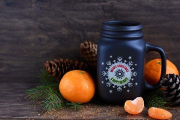 Wall Mural - Christmas, new year concept with mug of hot coffee with milk against rustic wooden background with spruce branches, cones, mandarins and nuts. Selective focus.